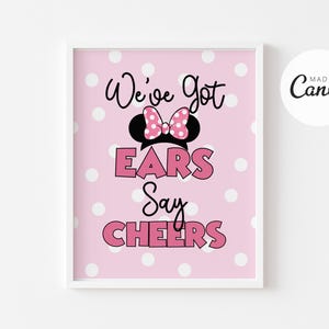 May include: Pink printable sign with white polka dots featuring a black and white silhouette of Minnie Mouse ears with a pink bow. The text reads "We've got ears say CHEERS".