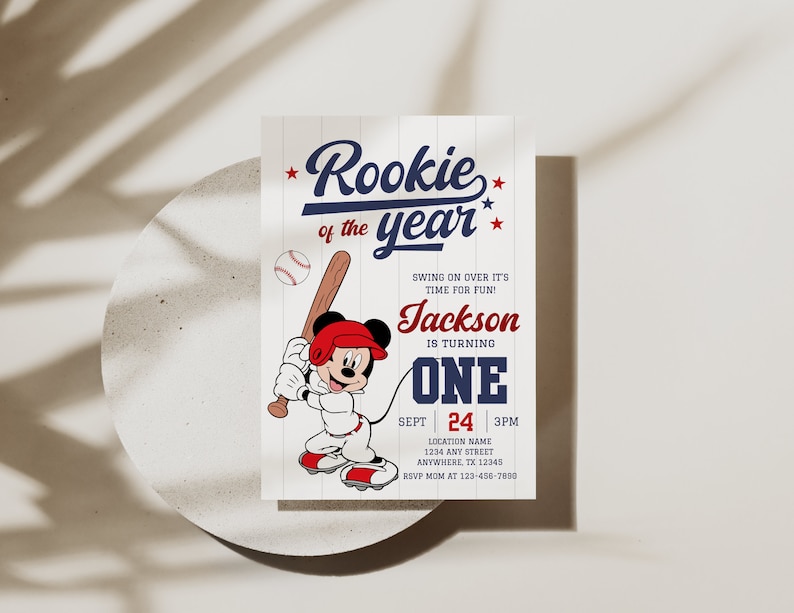 May include: Baseball-themed birthday invitation with a cartoon Mickey Mouse character holding a bat. The invitation says "Rookie of the year" and includes the name "Jackson" and the age "One".