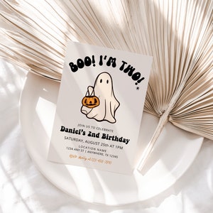 May include: A white card with a cartoon ghost holding a pumpkin bucket. The card says "BOO! I'M TWO!" and has the text "Join us to celebrate Daniel's 2nd Birthday" with details for the event.