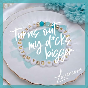 May include: A white beaded bracelet with gold letter beads spelling "Turns out my d*ck's bigger". The bracelet also features gold and turquoise beads. The bracelet is on a white plate with a gold rim, with the word "Lovercore" in the bottom right corner.