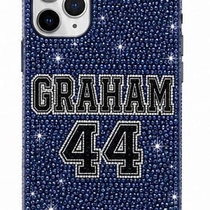 Könnte beinhalten: Eine dunkelblaue Smartphone-Hülle, die vollständig mit kleinen, funkelnden Kristallen bedeckt ist. In der Mitte befinden sich der Name GRAHAM und die Zahl 44 in einer schwarzen Schriftart im College-Stil mit weißem Kristallrand und strukturierter Oberfläche.