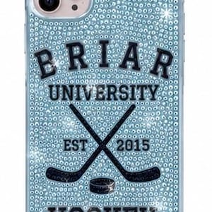 May include: A light blue phone case covered in sparkling rhinestones featuring the black text BRIAR UNIVERSITY, EST 2015, and HOCKEY. The design includes a graphic of two crossed black hockey sticks and a black hockey puck centered on the back.