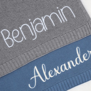 May include: Two knitted baby blankets, one gray with the name "Benjamin" embroidered in white, and one blue with the name "Alexander" embroidered in white.