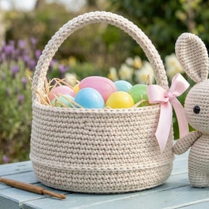 Peut inclure: Un panier de Pâques en crochet beige rempli d'œufs colorés et de paille, à côté d'un lapin en crochet avec un nœud rose. L'ensemble est posé sur une table bleue, avec un jardin en arrière-plan.