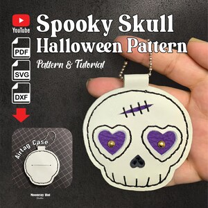 May include: White leather skull keychain with purple heart eyes and a stitched scar. The keychain is attached to a silver chain. The image includes the text "Spooky Skull Halloween Pattern" and "Pattern & Tutorial".
