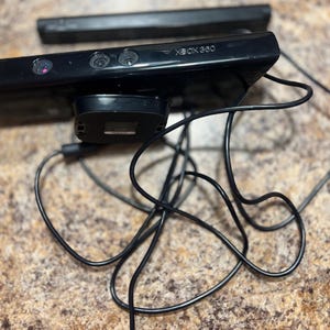 Peut inclure: Capteur Kinect noir pour Xbox 360 avec plusieurs lentilles et le logo Xbox 360. Le capteur a une base noire et un câble noir. Le capteur est conçu pour les jeux de détection de mouvement.