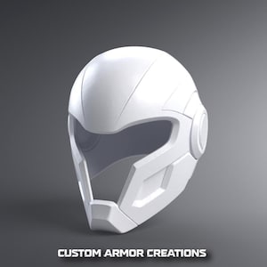 Könnte beinhalten: Ein mattweißer Integralhelm mit einer glatten, abgerundeten Helmschale, einer breiten Visieröffnung und geometrischen Seitenteilen mit kreisförmigen Ohrdetails. Der Text CUSTOM ARMOR CREATIONS ist unten im Bild weiß aufgedruckt.