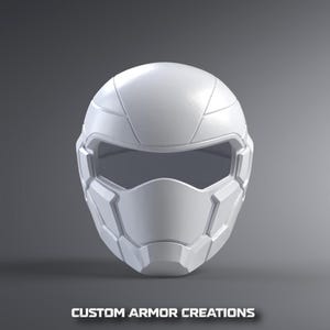 Puede incluir: Un casco integral blanco liso con una visera horizontal oscura y ancha, y paneles geométricos segmentados en la carcasa exterior. El texto CUSTOM ARMOR CREATIONS está impreso en letras mayúsculas blancas en la parte inferior.