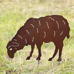 Può includere: Una silhouette di pecora in metallo arrugginito marrone che pascola in un campo di erba verde.