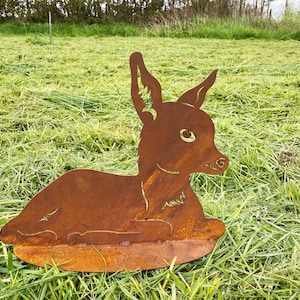 Könnte beinhalten: Eine rostige Metallskulptur eines liegenden Rehs. Die Skulptur ist detailliert mit einer strukturierten Oberfläche und einem realistischen Rehgesicht.