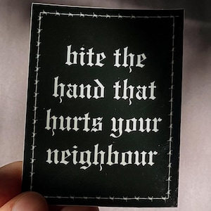 Peut inclure: Un autocollant rectangulaire noir avec une bordure en fil de fer barbelé blanc et le texte "bite the hand that hurts your neighbour" écrit dans une police gothique blanche. L'autocollant présente un design net avec un lettrage contrasté.