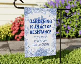 Könnte beinhalten: Eine weiße Gartenflagge mit blauen Blumenmustern und dem Text "GARDENING IS AN ACT OF RESISTANCE IT IS EASIER TO DESTROY THAN TO CREATE."