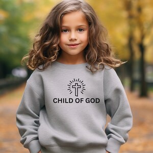 May include: A gray sweatshirt with a black graphic of a cross with a sunburst behind it and the text "CHILD OF GOD".