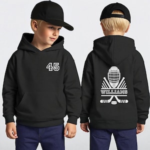 May include: Black hoodie with the number 45 in white on the front. The back of the hoodie features a hockey helmet, crossed hockey sticks, and the name "WILLIAMS" in white. The hoodie has a front pocket and a hood.