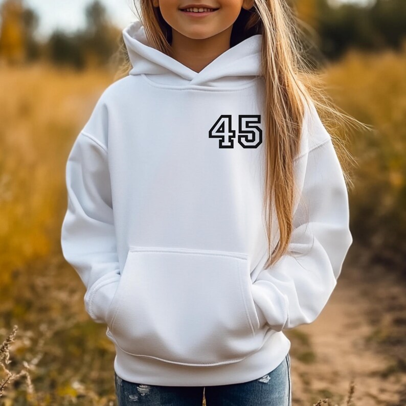 May include: A white hooded sweatshirt with a front pocket and the number "45" printed in black on the chest. The sweatshirt is made of a soft material and is suitable for casual wear.