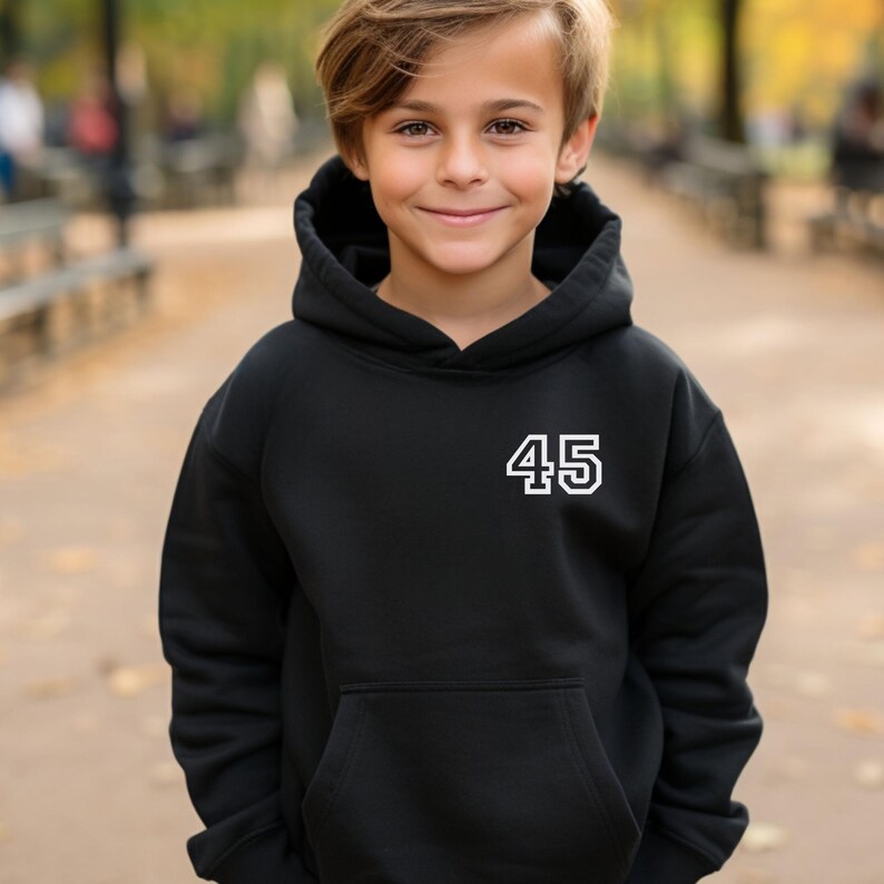 May include: A black hooded sweatshirt with a white number "45" on the upper left chest. The sweatshirt has a front pocket and a drawstring hood. The person in the image is wearing the sweatshirt.