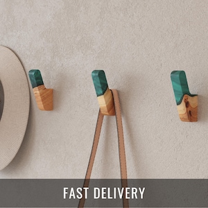 May include: A white ceramic mug with a black handle and the text "But First, Coffee" in a black, bold font. The mug is on a wooden surface. The mug is approximately 10 cm tall.