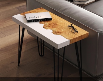 May include: A modern side table with a white and wood grain top, supported by black hairpin legs. The table features a book, glasses, and the text "OPEN TO CUSTOM SIZES". The wood grain has a unique, natural pattern.