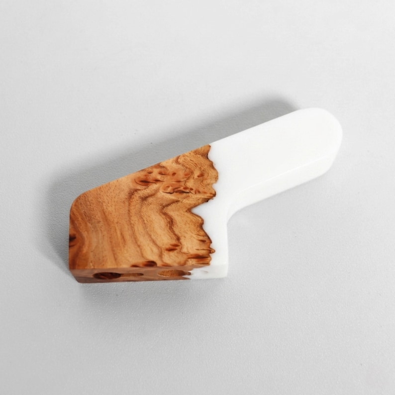 Op de afbeelding: Een handgemaakte houten handgreep met een witte harsgreep. De houtnerf is zichtbaar en toont een lichtbruine kleur. De handgreep is ontworpen met een gebogen vorm.