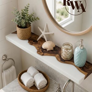 May include: A wall-mounted shelf featuring a natural live-edge wood center flanked by white sides. It holds a small potted plant in a woven basket, a white starfish, a seashell, a glass candle holder with rope netting, and a light blue soap dispenser.