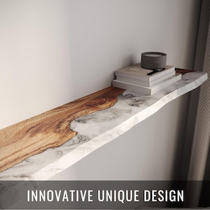 May include: A floating shelf with a unique design, featuring a combination of wood and marble-like resin. The shelf is adorned with a stack of books and a small, dark gray candle holder. The text "INNOVATIVE UNIQUE DESIGN" is displayed.
