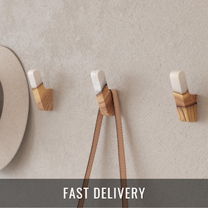 May include: Three wooden wall hooks with a light-colored finish and white accents. A tan leather strap hangs from one hook. The hooks are mounted on a light gray wall. The text "FAST DELIVERY" is displayed.