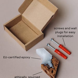 Op de afbeelding: Een houten en epoxy decoratief item met de tekst "EU-gecertificeerde epoxy" en "ethisch verantwoord massief hout". Inclusief schroeven en pluggen voor eenvoudige installatie. Het item zit in een kartonnen doos.