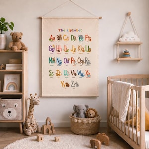 May include: A rectangular canvas wall hanging featuring the alphabet in colorful letters, each paired with a corresponding animal illustration and name. The text reads The alphabet, with letters A through Z displayed in rows on a light beige fabric.