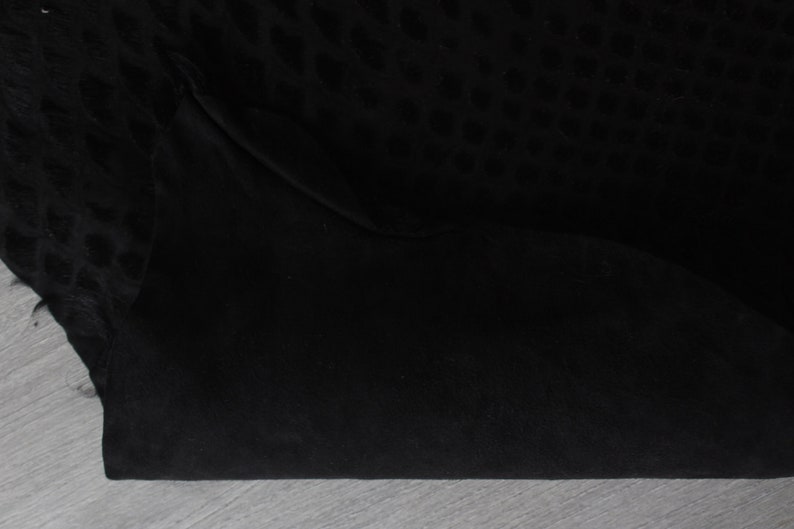 May include: Black fabric with a subtle leopard print pattern. The fabric is folded in half, showing the smooth texture of the material.