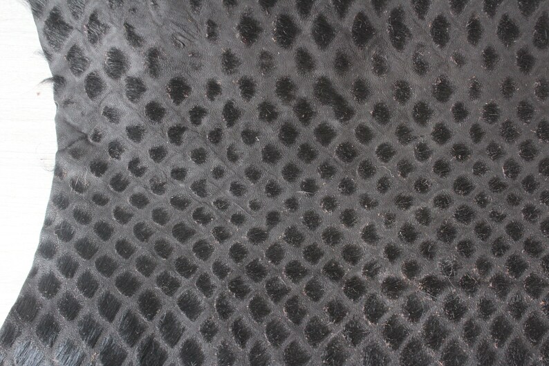 May include: Black leather with a textured, embossed pattern of small circles.