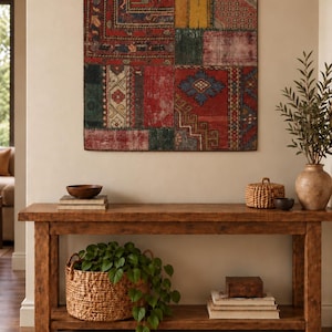 May include: A square wall hanging featuring a patchwork of vintage rug fragments in shades of red, yellow, green, and blue. The textile is mounted on three dark metal rings. The design consists of various geometric patterns and floral motifs.