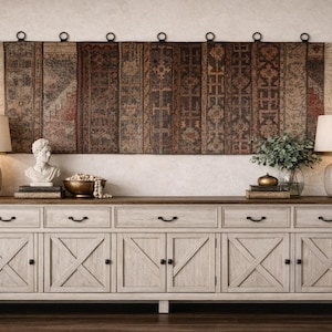 Op de afbeelding: Een rustiek, crèmekleurig houten dressoir met zes lades en deuren, bekroond met een donker houten oppervlak. Het heeft een decoratieve wandophanging, lampen en decor. Het dressoir is een stijlvolle opbergoplossing.