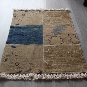 May include: A rectangular rug with a patchwork design. The rug has a blue, brown, and beige color scheme with a fringe border.