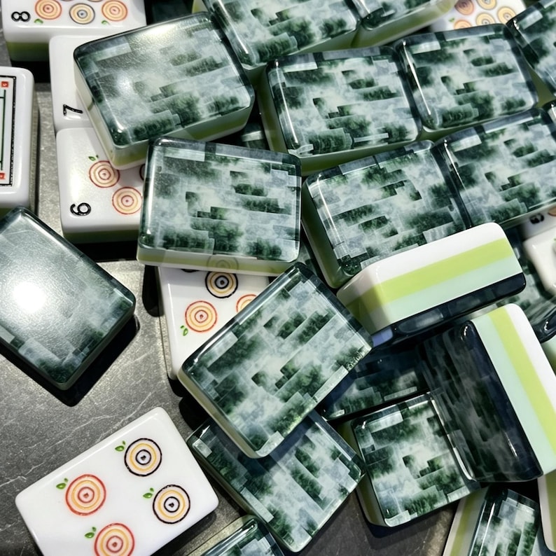 May include: A collection of rectangular mahjong tiles featuring a mix of white tiles with circular target-like patterns and green tiles with a marbled, cloudy texture. Some tiles display black numbers like 6, 7, and 8 on their white side edges.