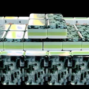 May include: A collection of rectangular mahjong tiles arranged in rows. The tiles feature a marbled black and white pattern on the top surface, with a distinct horizontal band of light green sandwiched between white layers on the sides of the tiles.