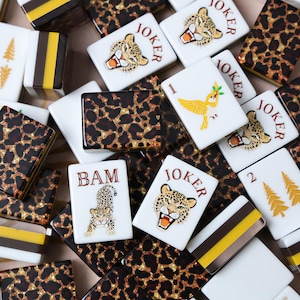 May include: A collection of rectangular mahjong tiles featuring various designs including leopard print patterns, gold and brown striped tiles, and white tiles with illustrations of leopards, a yellow bird, and the text JOKER and BAM.