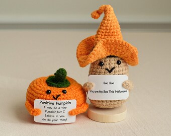 May include: Two crocheted Halloween decorations, a pumpkin and a boo with a witch hat. The pumpkin is orange and has a green stem. The boo is brown and has a black face. The pumpkin is holding a card that says "Positive Pumpkin I may be a tiny Pumpkin, but I Believe in you. Go do your thing!" The boo is holding a card that says "Boo Boo You are My Boo This Halloween!"
