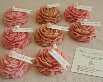 May include: Assortment of eight handmade rose-shaped candles in pink and brown shades. Each candle has a small tag attached with the text "Magic Candle Studio".