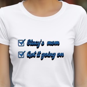 Puede incluir: Camiseta blanca con el texto azul "Stacy's mom Got it going on". La camiseta tiene cuello redondo y mangas cortas. El logotipo de Boxcar Bandit Apparel está en la esquina superior izquierda.