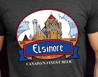 May include: A dark heather grey t-shirt with a vintage-style illustration of a castle and the text "Elsinore" in a blue banner. The text "Canada's Finest Beer" is printed below the illustration.