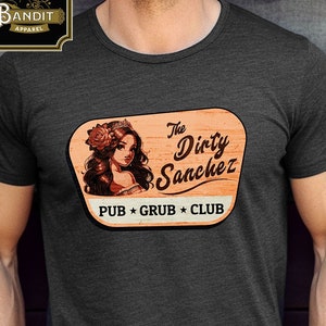 May include: A dark gray t-shirt with a vintage-style logo featuring a woman with a flower in her hair. The logo says "The Dirty Sanchez Pub * Grub * Club".