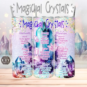 Puede incluir: Tres vasos de acero inoxidable con fondo brillante y diseños de cristales coloridos. Cada vaso presenta un tema de cristal diferente: Felicidad, Éxito, Protección, Dinero, Amor, Fertilidad, Concentración, Sueño, Claridad. Los vasos están decorados con los nombres de los cristales y sus propiedades asociadas.