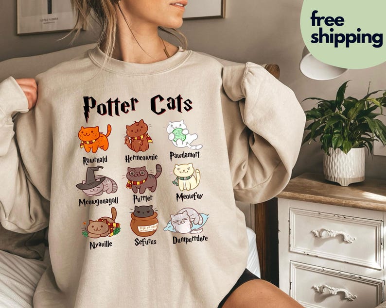 Peut inclure: Un sweat-shirt beige avec un graphique de chats avec des noms de personnages d'Harry Potter. Le texte "Potter Cats" est en haut du graphique. Les noms des chats sont : Rownald, Hermoine, Pawdamort, Meowgonagall, Purrter, Meowfox, Nyaville, Seffurus et Dumpldore.
