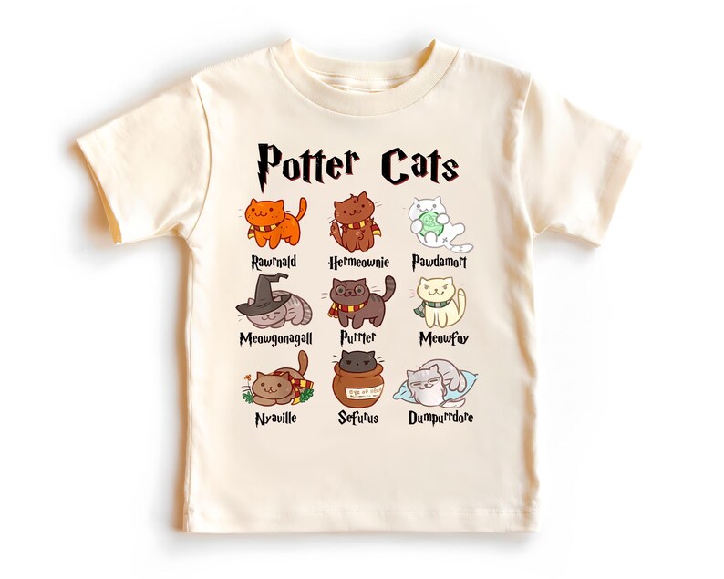 Peut inclure: Un t-shirt cr&egrave;me avec un graphique de chats repr&eacute;sentant des personnages de la s&eacute;rie Harry Potter. Le texte "Potter Cats" est imprim&eacute; en noir au-dessus du graphique. Les noms des personnages sont imprim&eacute;s sous chaque chat.