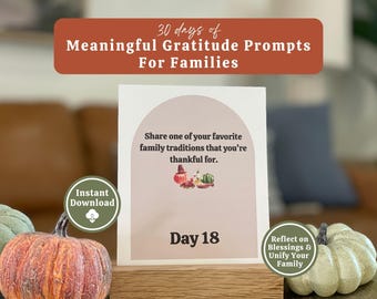May include: A card with the text "30 days of Meaningful Gratitude Prompts For Families" and "Share one of your favorite family traditions that you're thankful for." Day 18 is displayed. The card is on a wooden stand with pumpkins.