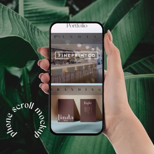 Könnte beinhalten: Ein Telefon-Mockup, das eine Website für ein Branding- und Designunternehmen namens "Fineprintco" zeigt. Die Website zeigt ein Foto einer Bar mit Hockern und den Text "Branding" und "Portfolio". Das Telefon wird in einer Hand vor einem grünen, blättrigen Hintergrund gehalten.