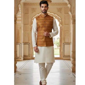 May include: A man wearing a traditional Indian outfit. The ensemble includes a cream-colored kurta and pants, paired with a patterned gold and brown vest. The outfit is completed with brown shoes.