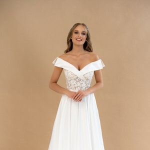 Enchanteresse robe de mariée avec son col marquise et sa jupe à plis plats en satin