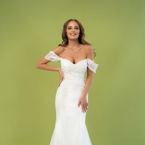 Peut inclure: Une robe de mariée blanche à épaules dénudées avec des embellissements floraux et une jupe fluide.