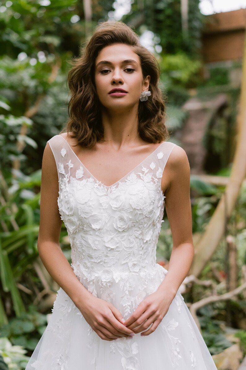 Imaginez vous dans cette robe de mariée envoûtante qui vous transportera dans un univers de féérie le jour de votre mariage. La dentelle florale en 3D ajoute une touche de magie, vous faisant étinceler sous les projecteurs.